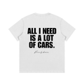White heavyweight cotton car enthusiast t-shirt featuring bold black typography reading "All I Need Is A Lot Of Cars" with a subtle "Driven by obsession" script on the back