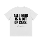 White heavyweight cotton car enthusiast t-shirt featuring bold black typography reading "All I Need Is A Lot Of Cars" with a subtle "Driven by obsession" script on the back