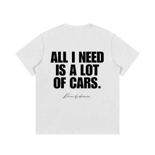 White heavyweight cotton car enthusiast t-shirt featuring bold black typography reading "All I Need Is A Lot Of Cars" with a subtle "Driven by obsession" script on the back