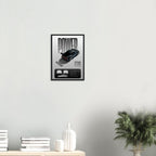 Framed poster with a car design on a wall above a shelf with decorative items.