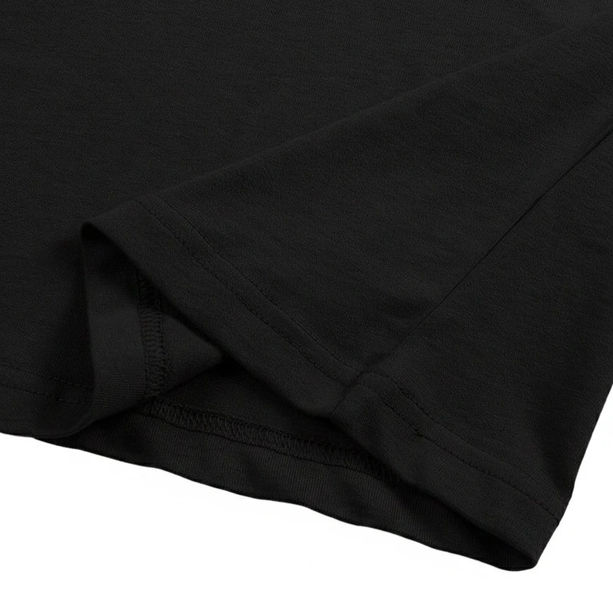 Close-up of the black cotton jersey fabric hem, showing the neat double-needle stitching detail.
