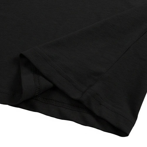 Close-up of the black cotton jersey fabric hem, showing the neat double-needle stitching detail.